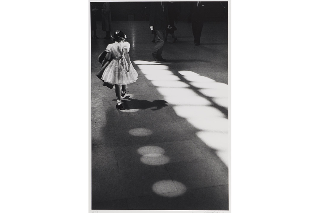 Black and white image of a girl in a white dress seen from the back