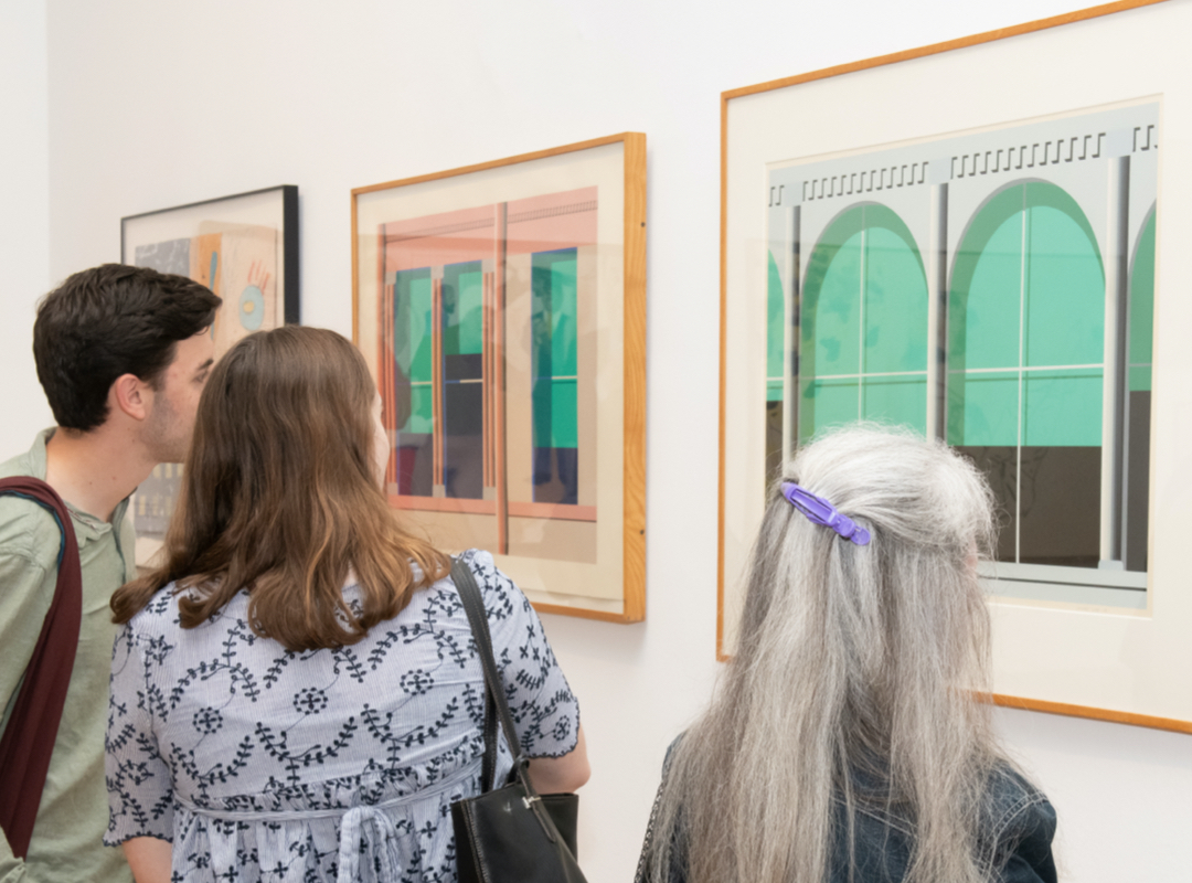 three people looking at paintings