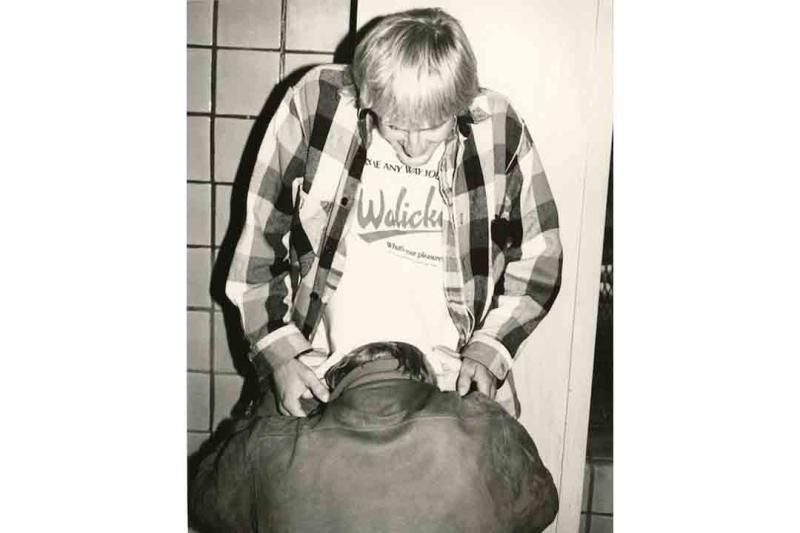 man kneeling in front of other man against a tile wall